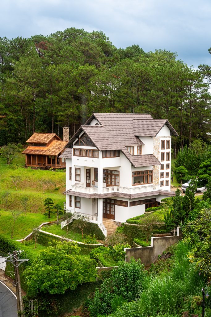White villa nestled in green landscape of Da Lat, Vietnam, offering scenic and tranquil vibes.